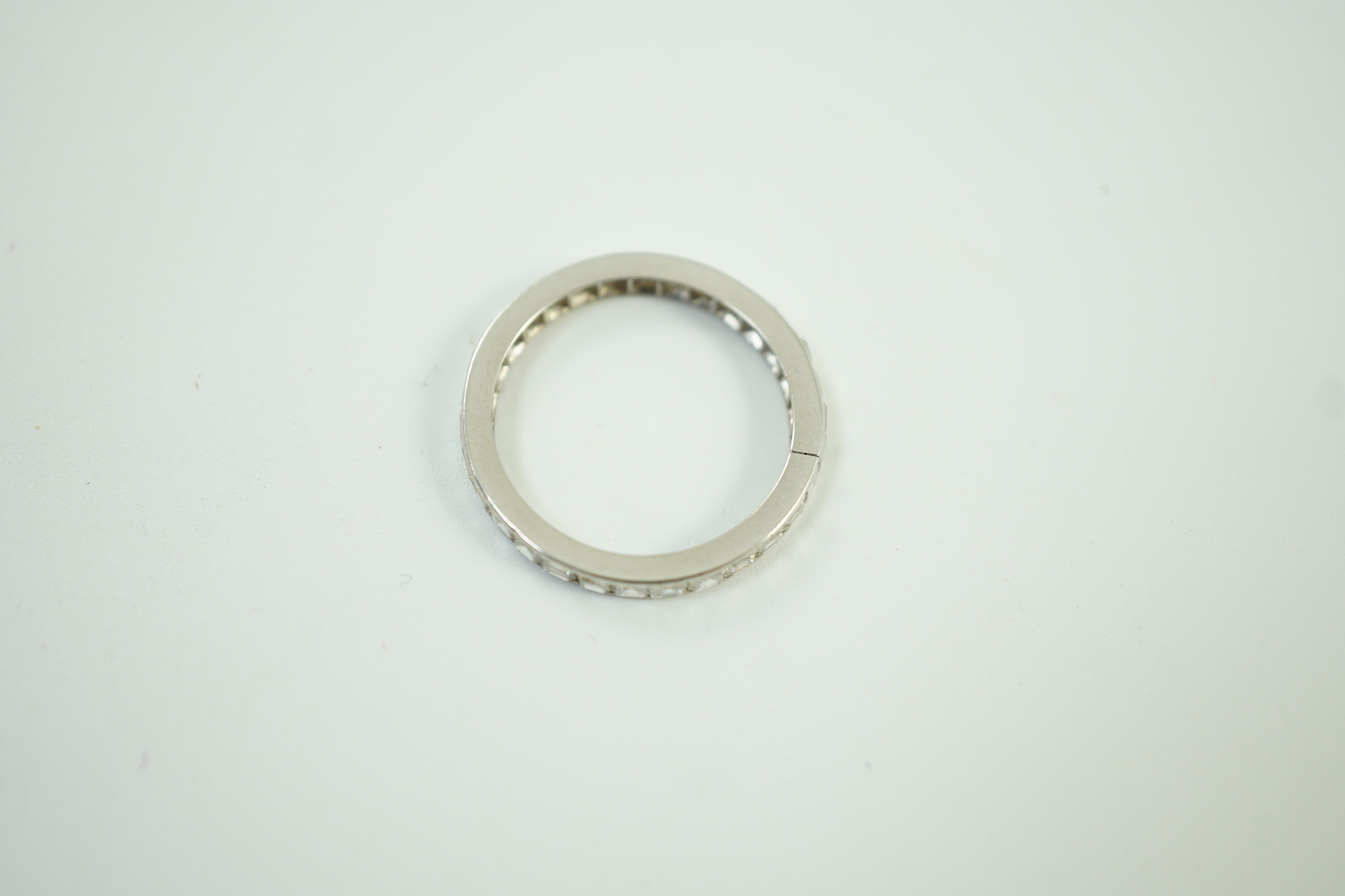 A white metal and square cut diamond set full eternity ring, size M/N, gross weight 2.3 grams.